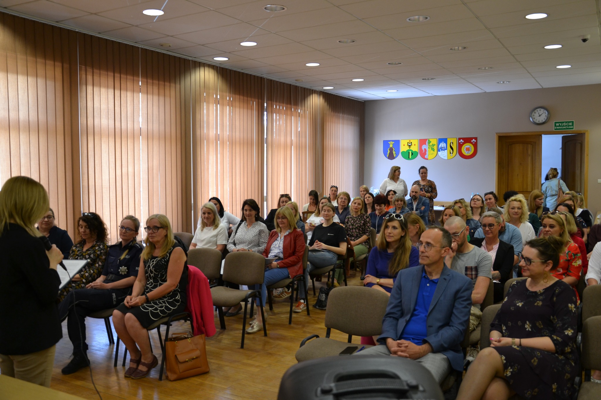 Sala szkoleniowa. Słuchacze siedzą na krzesłach w dwóch rzędach